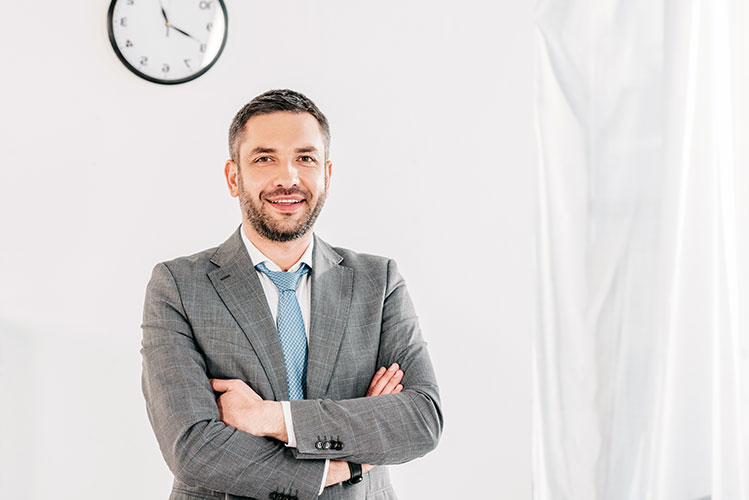 handsome smiling businessman in suit with crossed arms looking a